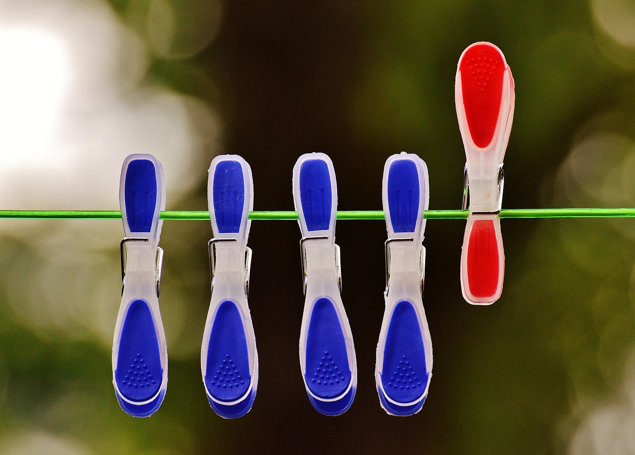 4 blaue Wäscheklammer auf einer Leine, die nach unten zeigen. Daneben eine rote Wäscheklammer, die nach oben zeigt